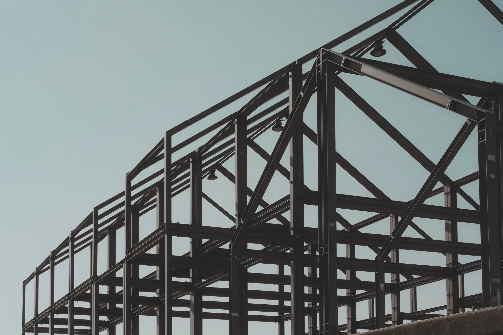 Bare structural steel frame of a new building against a pale sky